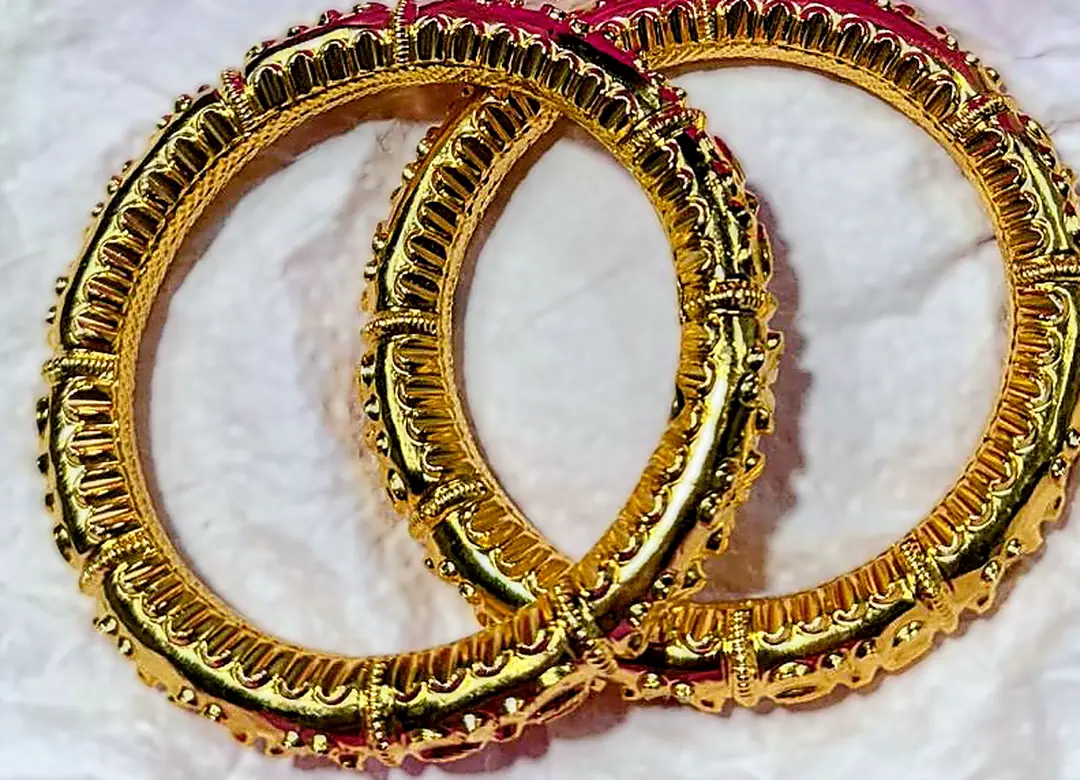 Two gold bangles resting on white tissue paper on my bench. The paper is close enough to neutral that the camera needed almost no correction, and the gold reads as gold rather than orange.