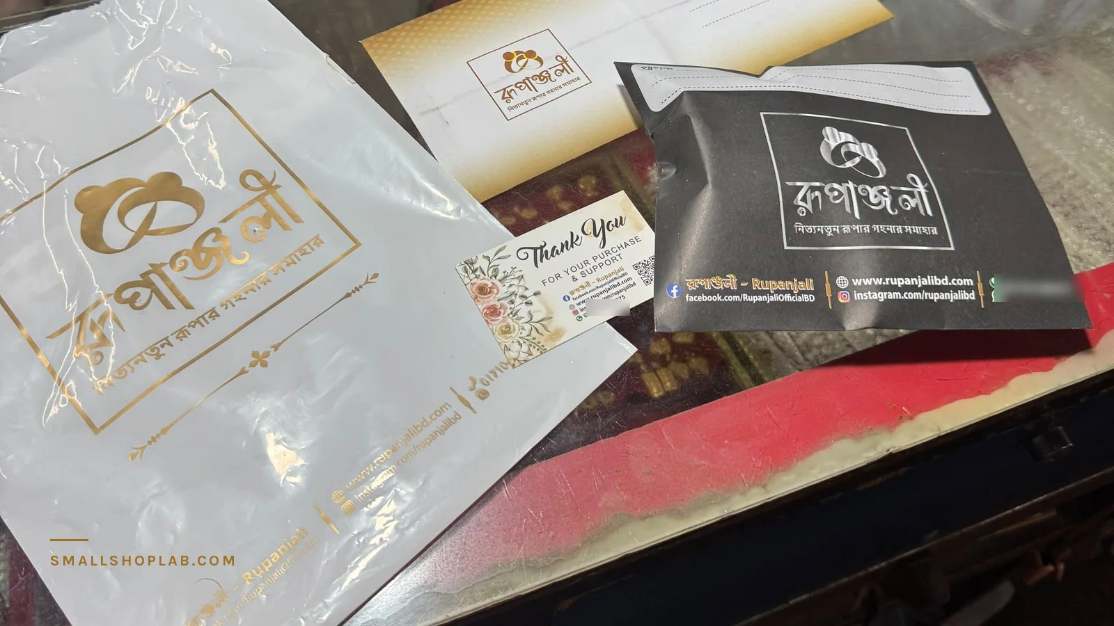 The real packaging from my own silver shop, photographed on the shop counter: a printed poly mailer, a courier bag with its document pouch, a kraft envelope and the thank-you card that carries my contact details.
