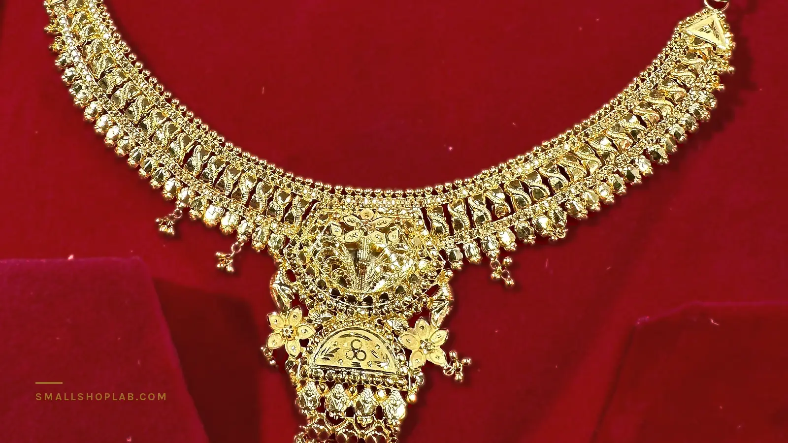 A gold necklace lying in a red velvet box, photographed on a phone in my own shop. The velvet fills most of the frame and its red is strong enough to have almost no green or blue in it at all.